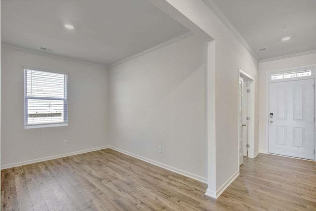 foyer entrance with light wood-style floors, baseboards, and ornamental molding