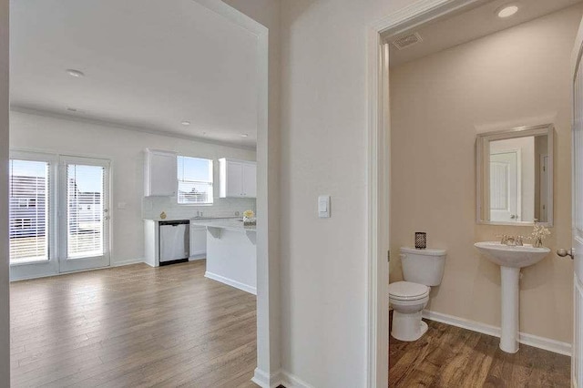 half bath featuring decorative backsplash, toilet, a sink, wood finished floors, and baseboards