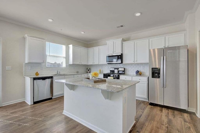 kitchen featuring visible vents, white cabinets, appliances with stainless steel finishes, wood finished floors, and a sink