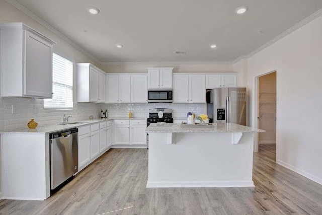 kitchen featuring decorative backsplash, appliances with stainless steel finishes, ornamental molding, light wood-type flooring, and white cabinetry