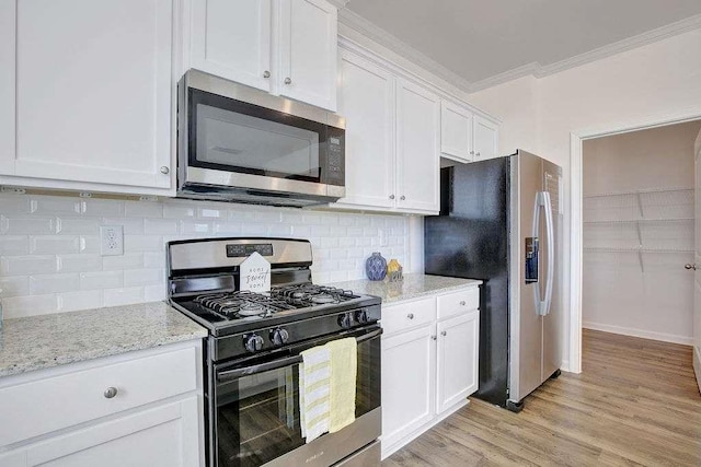 kitchen with light stone counters, stainless steel appliances, white cabinets, ornamental molding, and light wood finished floors