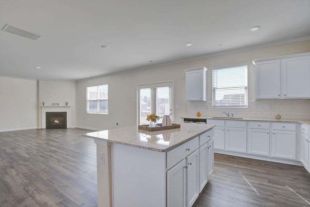 kitchen featuring a warm lit fireplace, visible vents, decorative backsplash, and dark wood-type flooring