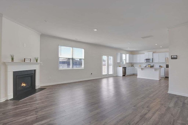 unfurnished living room with ornamental molding, dark wood-style flooring, a fireplace with flush hearth, and baseboards