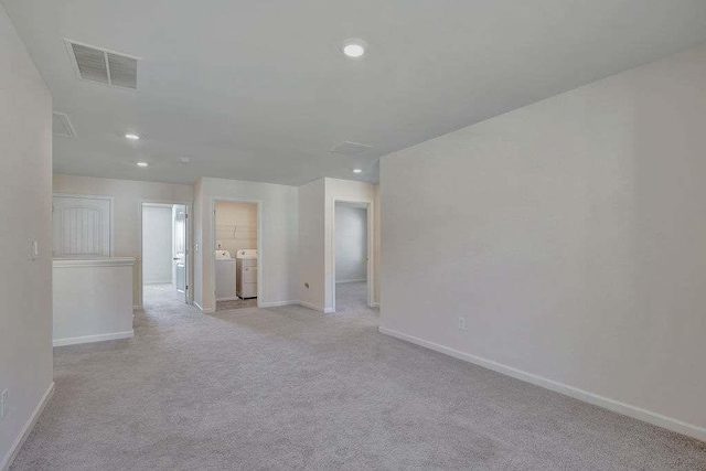 spare room featuring visible vents, baseboards, light colored carpet, washing machine and dryer, and recessed lighting