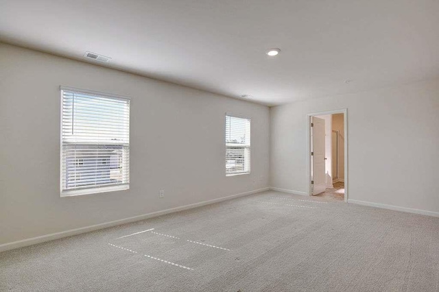 spare room featuring light colored carpet, visible vents, baseboards, and recessed lighting