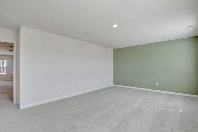 empty room with recessed lighting, light colored carpet, visible vents, and baseboards