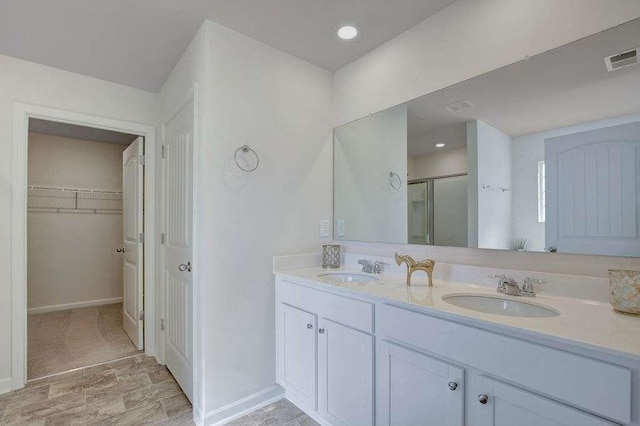 bathroom with a walk in closet, a sink, visible vents, and a shower stall