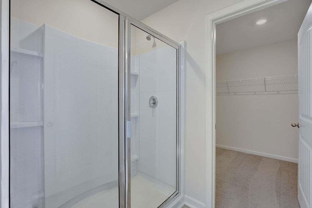 bathroom with a stall shower, a walk in closet, and baseboards