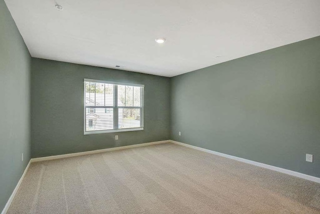 spare room featuring light carpet and baseboards