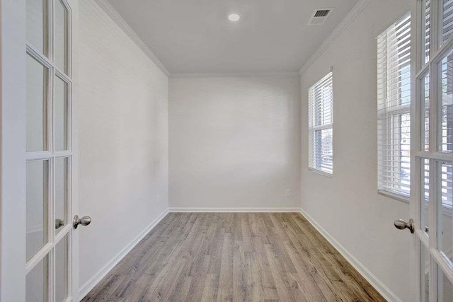 empty room with ornamental molding, visible vents, light wood-style floors, and baseboards