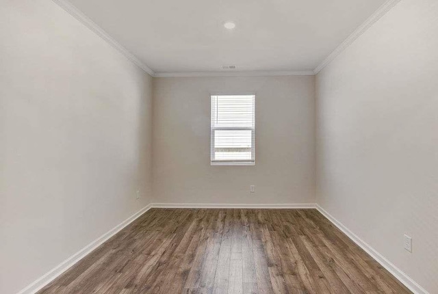 empty room with baseboards, visible vents, ornamental molding, and wood finished floors