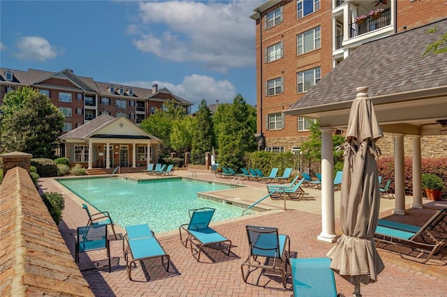 community pool with a ceiling fan, a patio area, fence, and an outdoor structure