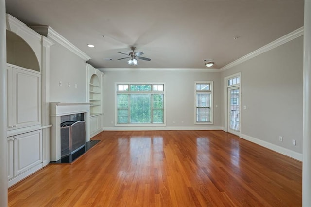 unfurnished living room featuring crown molding, a fireplace, ceiling fan, light wood finished floors, and baseboards