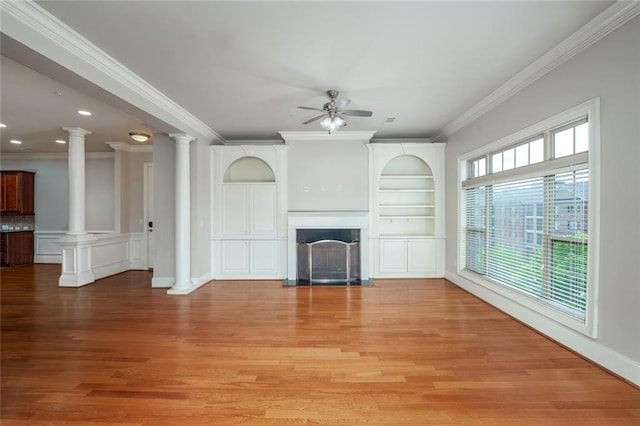 unfurnished living room featuring a ceiling fan, light wood finished floors, decorative columns, ornamental molding, and built in features