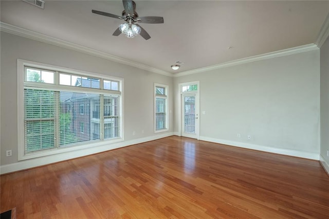 empty room with baseboards, wood finished floors, crown molding, and ceiling fan