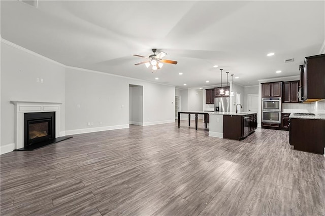 unfurnished living room featuring dark hardwood / wood-style flooring, sink, crown molding, and ceiling fan