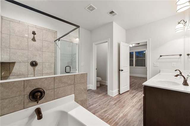 full bathroom featuring toilet, wood-type flooring, shower with separate bathtub, and vanity