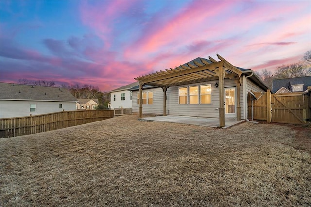 back house at dusk featuring a patio, a lawn, and a pergola