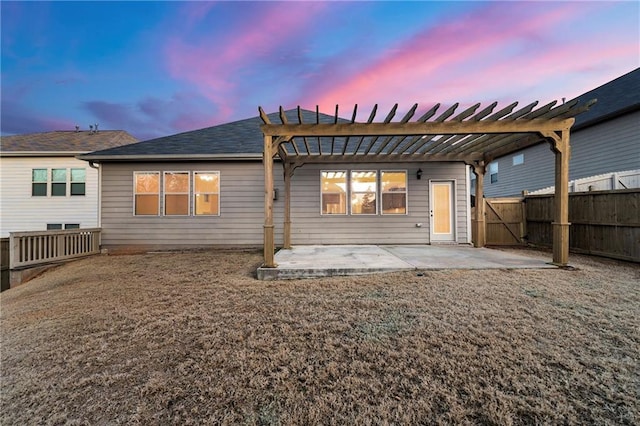 back house at dusk featuring a yard, a pergola, and a patio area