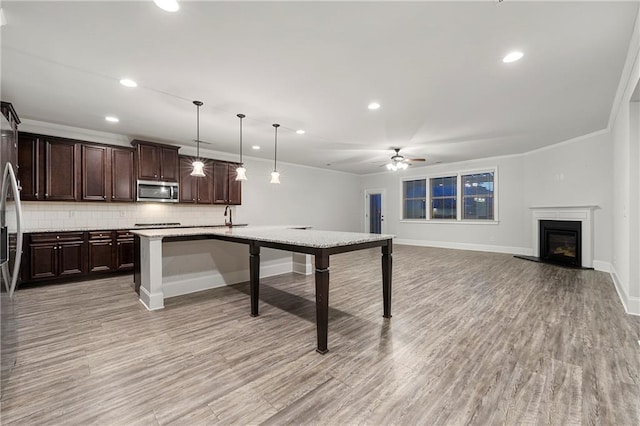 kitchen featuring a breakfast bar area, an island with sink, pendant lighting, stainless steel appliances, and decorative backsplash