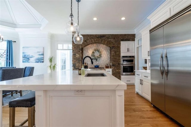 kitchen with stainless steel appliances, a large island with sink, sink, and white cabinets