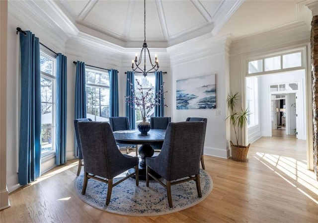 dining room with crown molding, a towering ceiling, an inviting chandelier, and light wood-type flooring