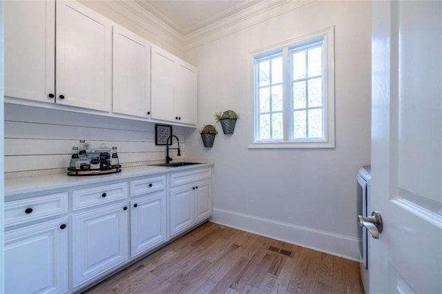 washroom featuring crown molding, sink, and light hardwood / wood-style flooring