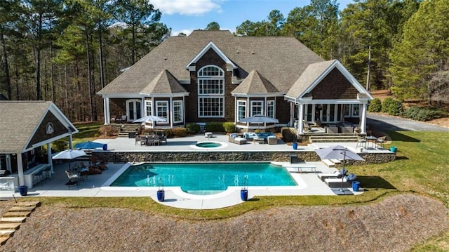 rear view of house featuring an outdoor structure, a pool with hot tub, a yard, and a patio area