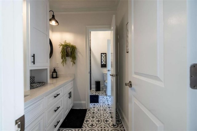 bathroom with ornamental molding, vanity, toilet, and tile patterned flooring