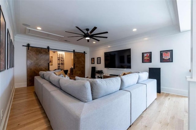 living room with ceiling fan, ornamental molding, a barn door, and light hardwood / wood-style floors