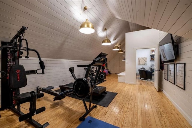 exercise room with lofted ceiling, wooden ceiling, and light wood-type flooring