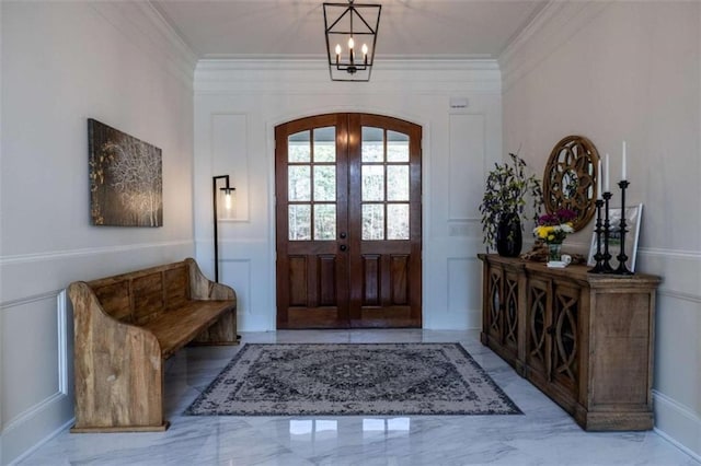 entrance foyer featuring french doors, ornamental molding, and a notable chandelier