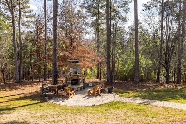 view of yard with an outdoor stone fireplace and a patio area