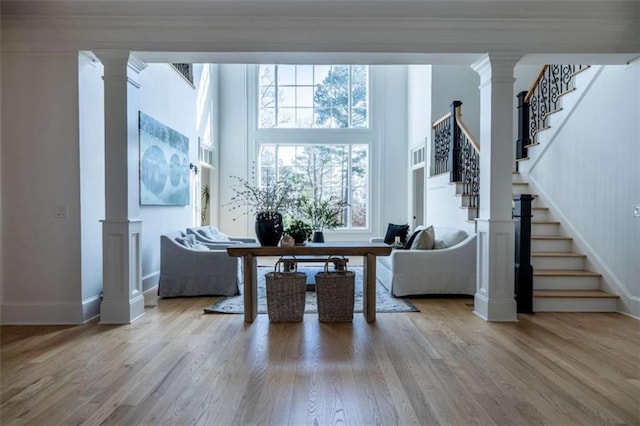 living room featuring crown molding, hardwood / wood-style flooring, a high ceiling, and ornate columns