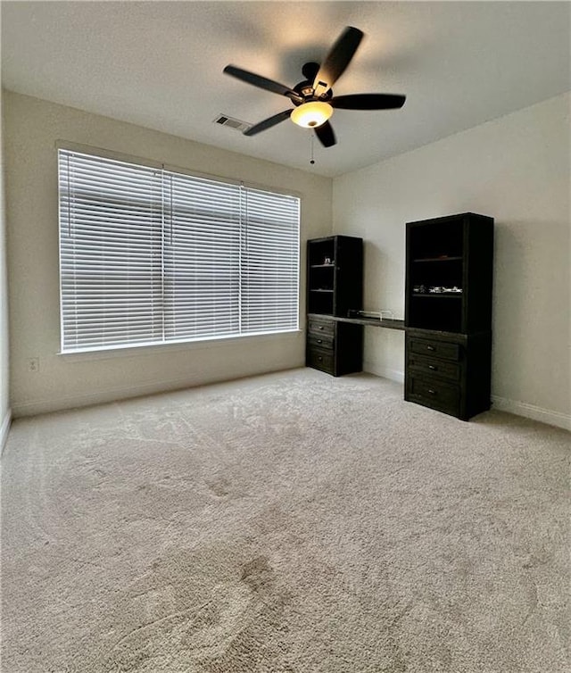 unfurnished bedroom featuring multiple windows, carpet flooring, and ceiling fan