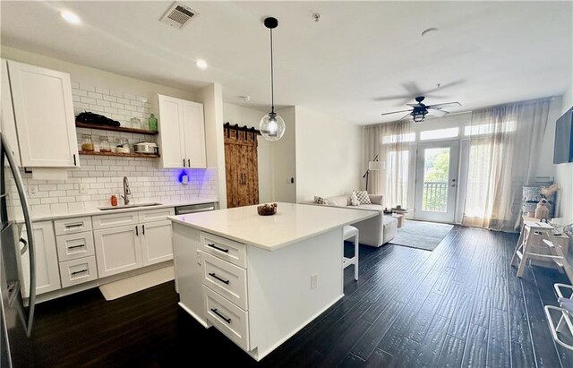 kitchen with sink, decorative light fixtures, a barn door, and white cabinetry