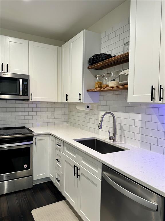 kitchen featuring stainless steel appliances, sink, and white cabinetry