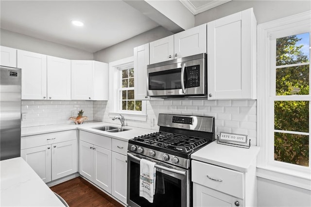 kitchen with a sink, stainless steel appliances, light countertops, white cabinets, and tasteful backsplash