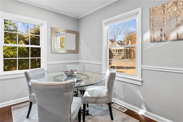 dining area featuring visible vents, wood finished floors, baseboards, and ornamental molding