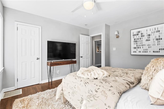 bedroom with ceiling fan, wood finished floors, visible vents, and baseboards