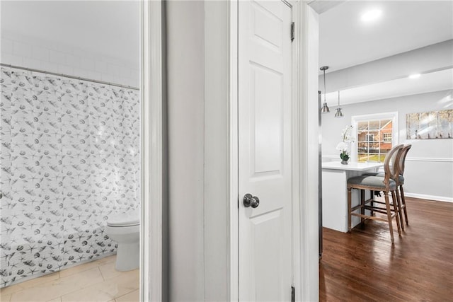 full bath with a shower with curtain, toilet, and wood finished floors