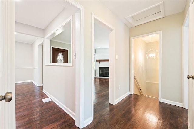 hall featuring an upstairs landing, attic access, baseboards, and dark wood-style flooring