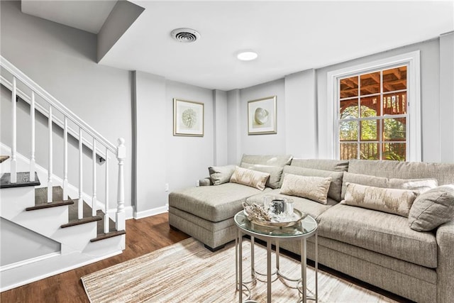 living room featuring visible vents, baseboards, wood finished floors, and stairs