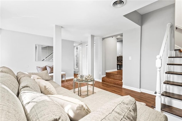 living area featuring visible vents, stairs, baseboards, and wood finished floors