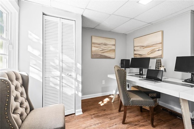 office area featuring baseboards, a paneled ceiling, and light wood finished floors