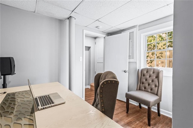 home office featuring a drop ceiling, baseboards, and wood finished floors