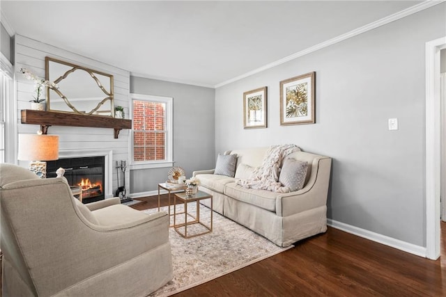 living area featuring baseboards, wood finished floors, a glass covered fireplace, and crown molding