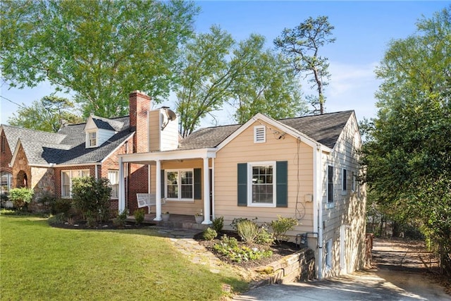 view of front of property featuring covered porch, a chimney, and a front lawn