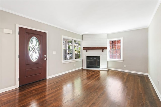 foyer featuring a fireplace, wood finished floors, baseboards, and ornamental molding