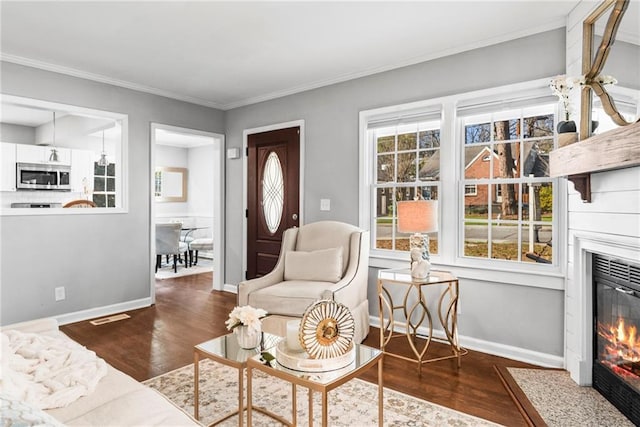 living area featuring crown molding, a fireplace with flush hearth, wood finished floors, and baseboards